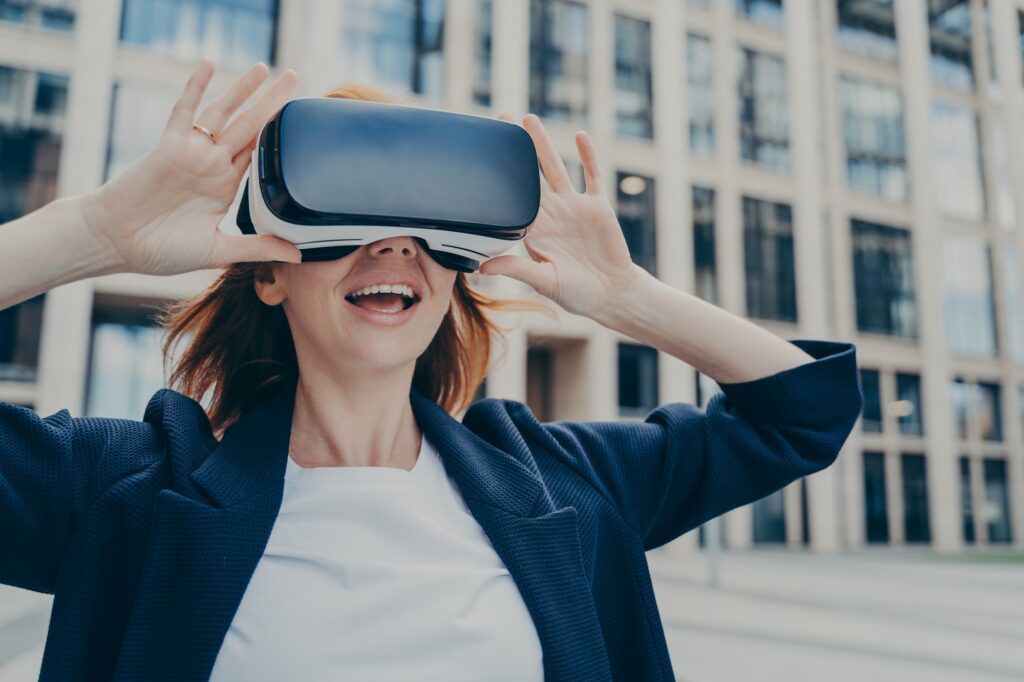 Excited businesswoman exploring virtual reality with VR headset outdoors